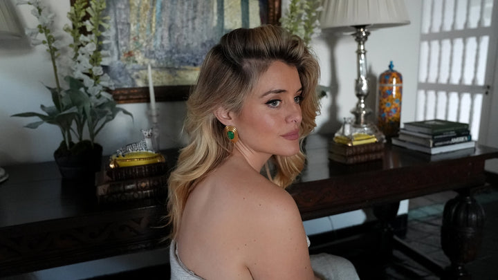 Daphne Oz looking into mirror showing reflection of her wearing gold charm necklace from her jewellery collaboration with Soru 