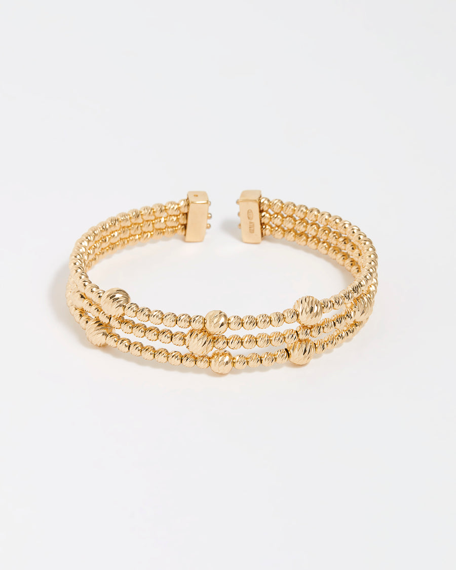 Product shot of a triple gold textured beaded cuff on a white background