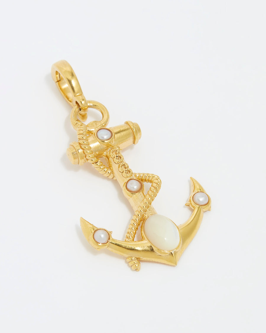 close up image shot of gold anchor charm with white embellishment and a rope twist detail on a white background