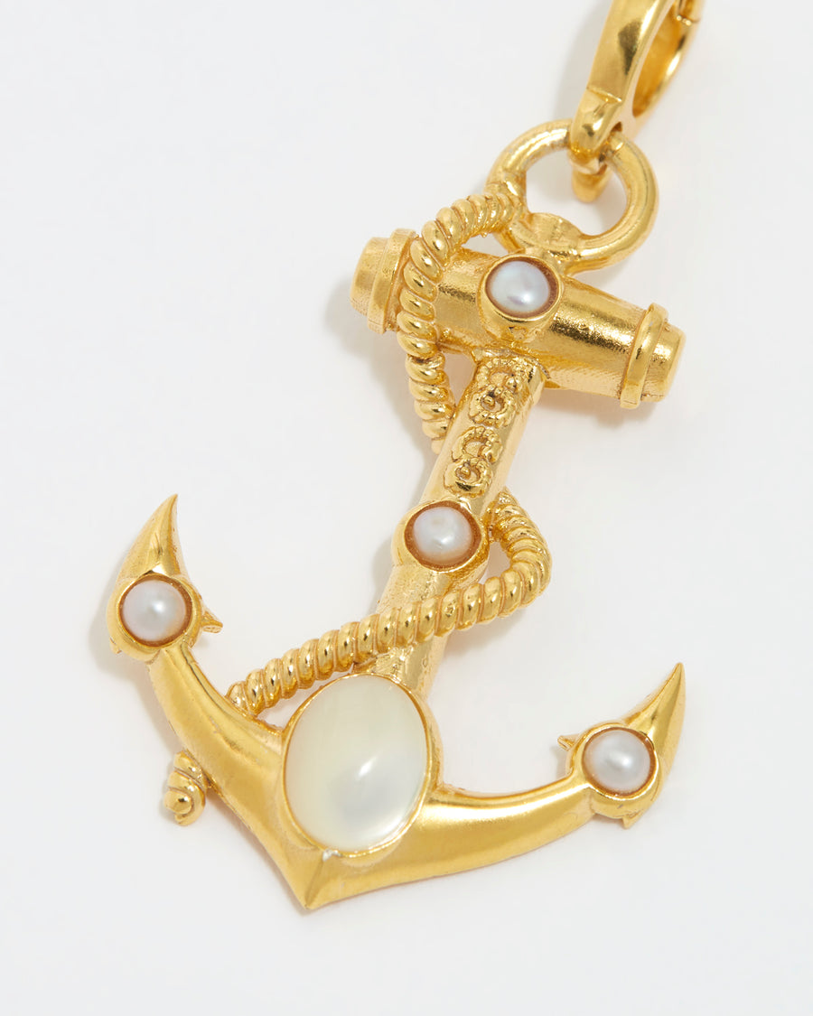 Close up overhead image of the white embellished gold anchor charm with rope twist detail on white background