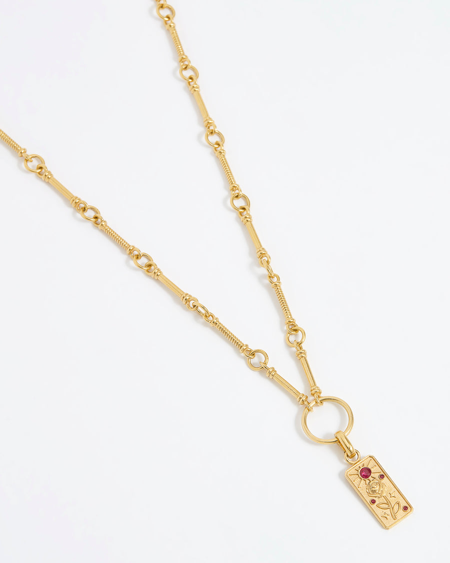 Product shot of gold textured charm hung from a gold link charm chain on white background