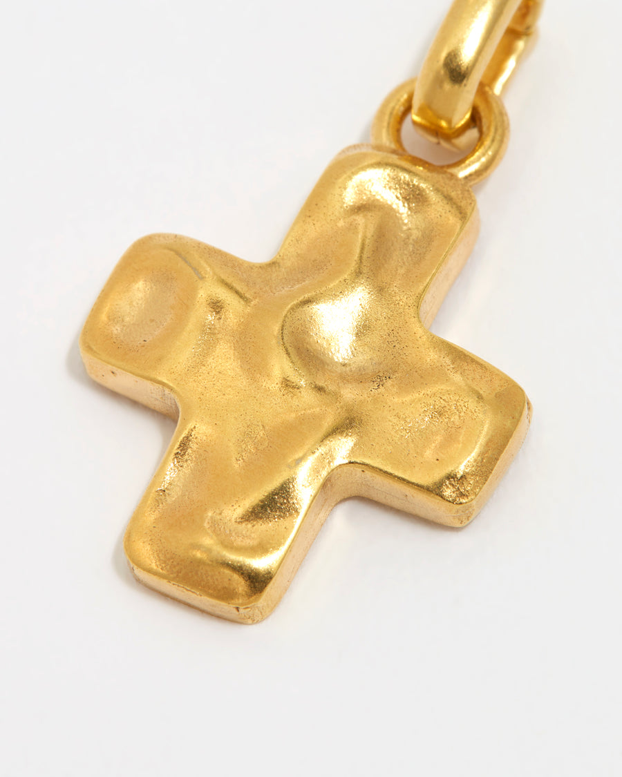 close up overhead image of soru jewellery detachable gold cross charm on a white background