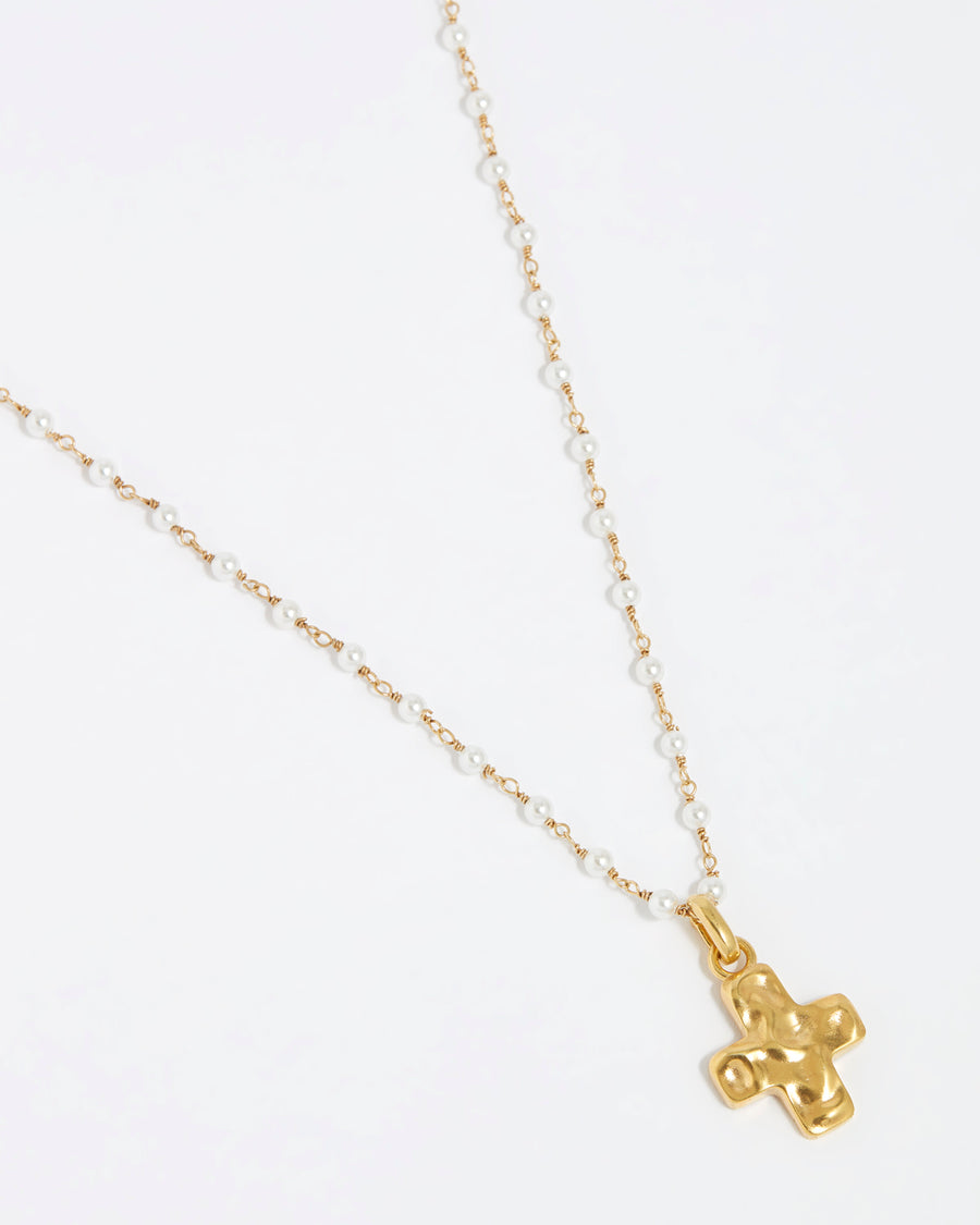 product shot of detachable gold cross charm hanging from a pearl beaded charm chain on a white background