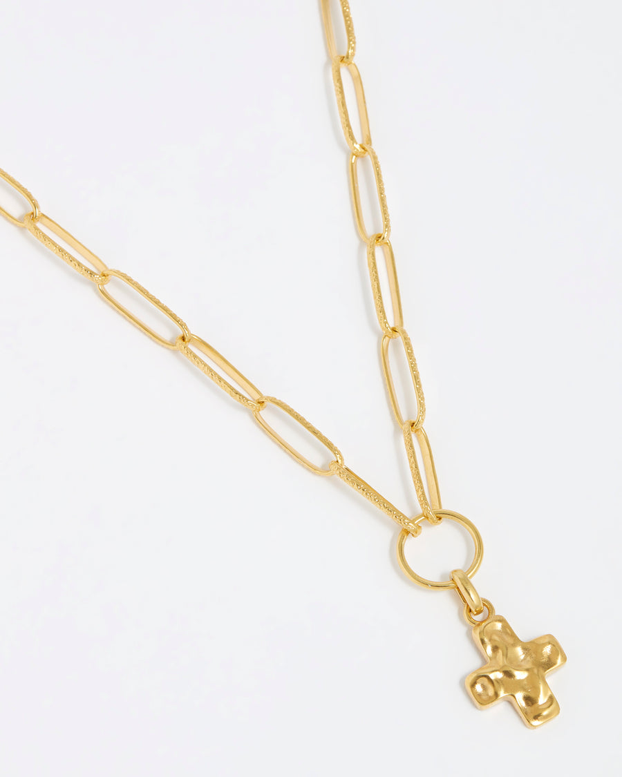 product shot of detachable gold cross charm hanging from a gold charm chain on a white background