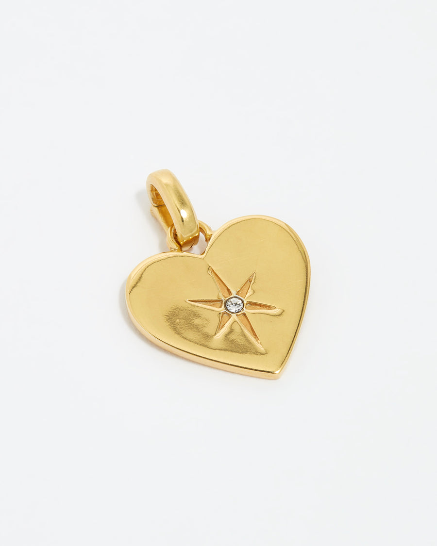 close up image shot clear crystal surrounded by a star etching set in a shiny gold heart.