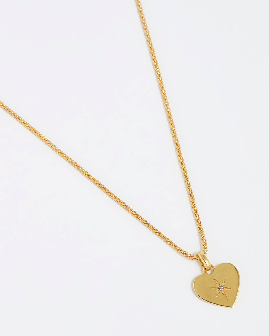 product shot of a clear crystal surrounded by a star etching set in a shiny gold heart hung from a gold rope chain on a white background