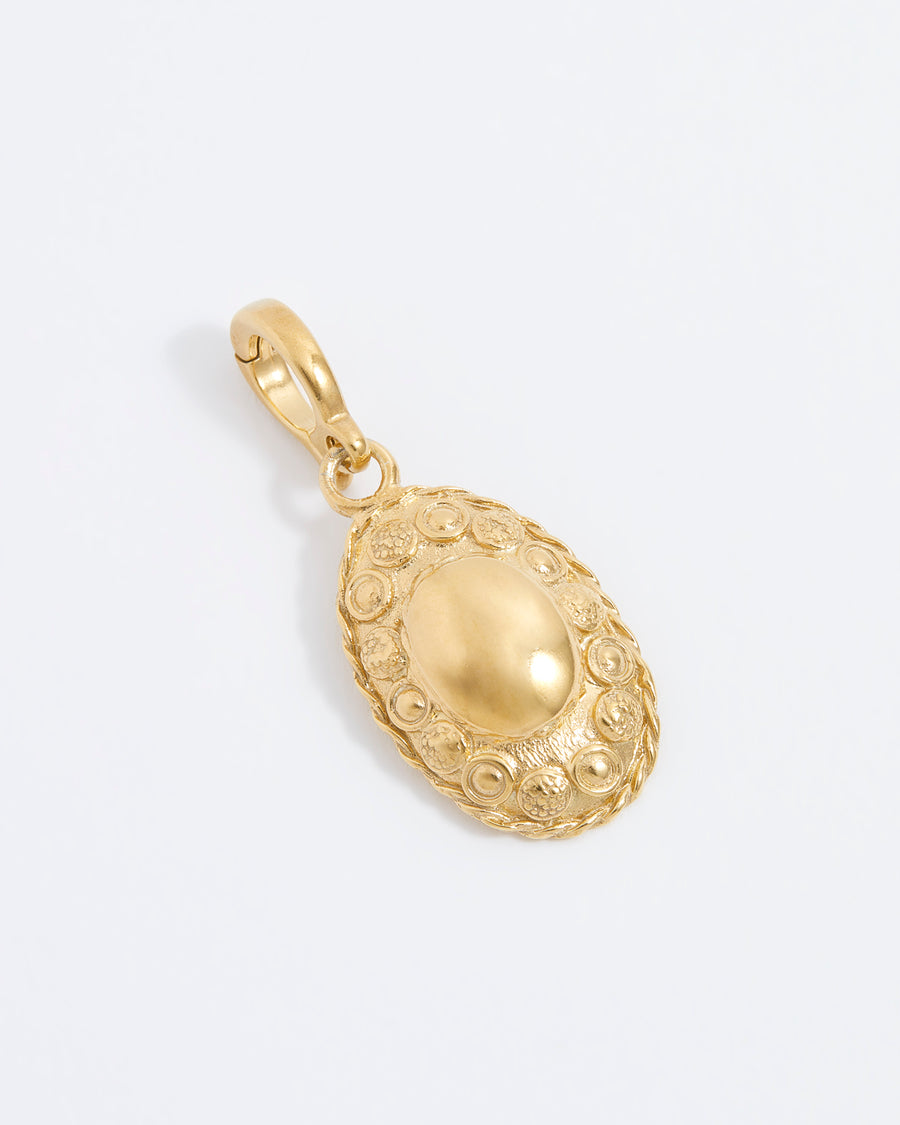 Gold oval charm with intricate embossed patterns and a smooth central dome, featuring a small clasp for attachment.