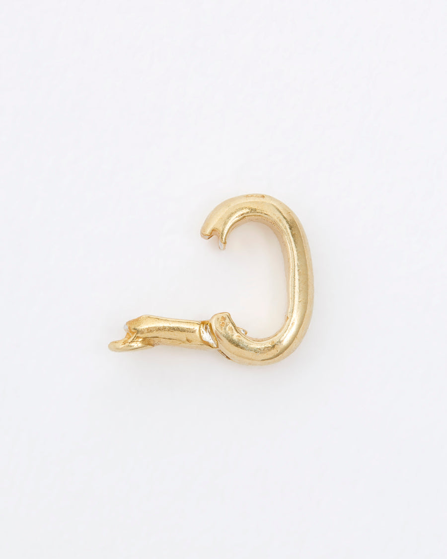 Open gold clasp used for charm necklaces on grey background