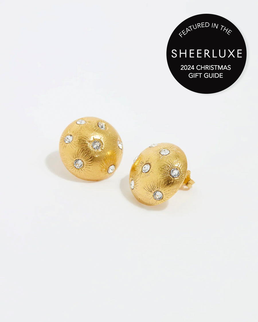 close up image shot of round gold star etched earrings with clear crystal embellishment on a white back ground