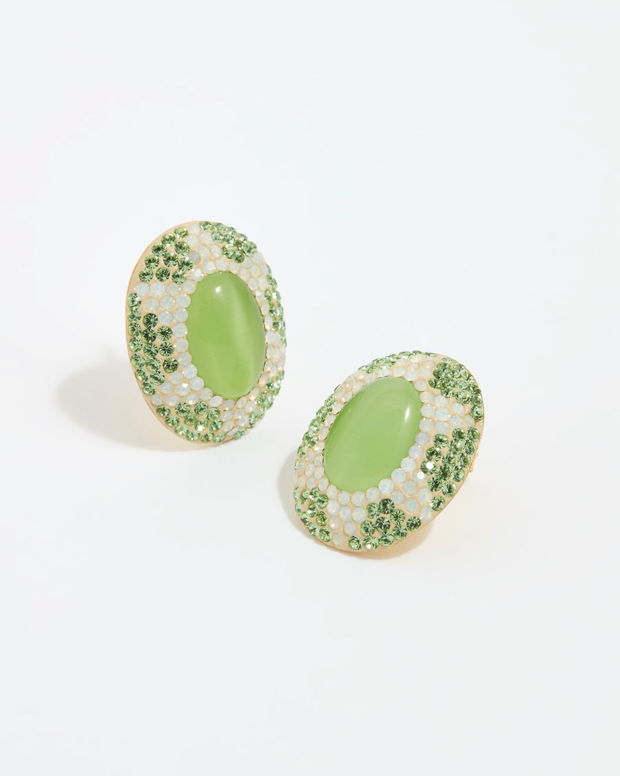 close up image shot of oval stud earrings featuring a vibrant green cats eye stone surrounded by sparkling green and opal crystals set with a sun motif on a white back ground
