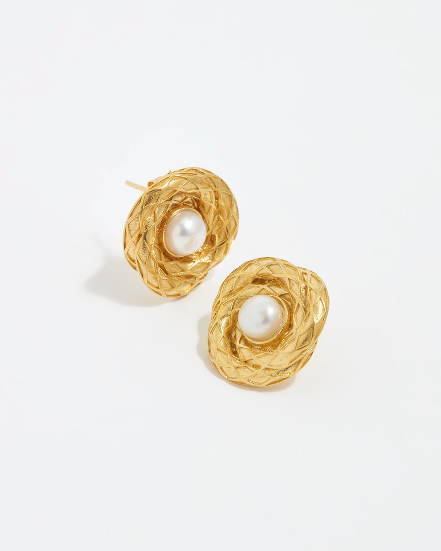 close up image shot of round gold textured earrings with centre pearl on a white back ground