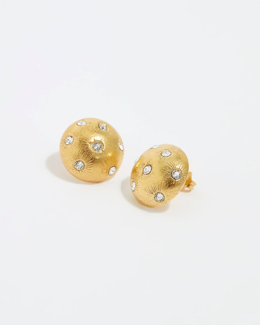 close up image shot of round gold star etched earrings with clear crystal embellishment on a white back ground