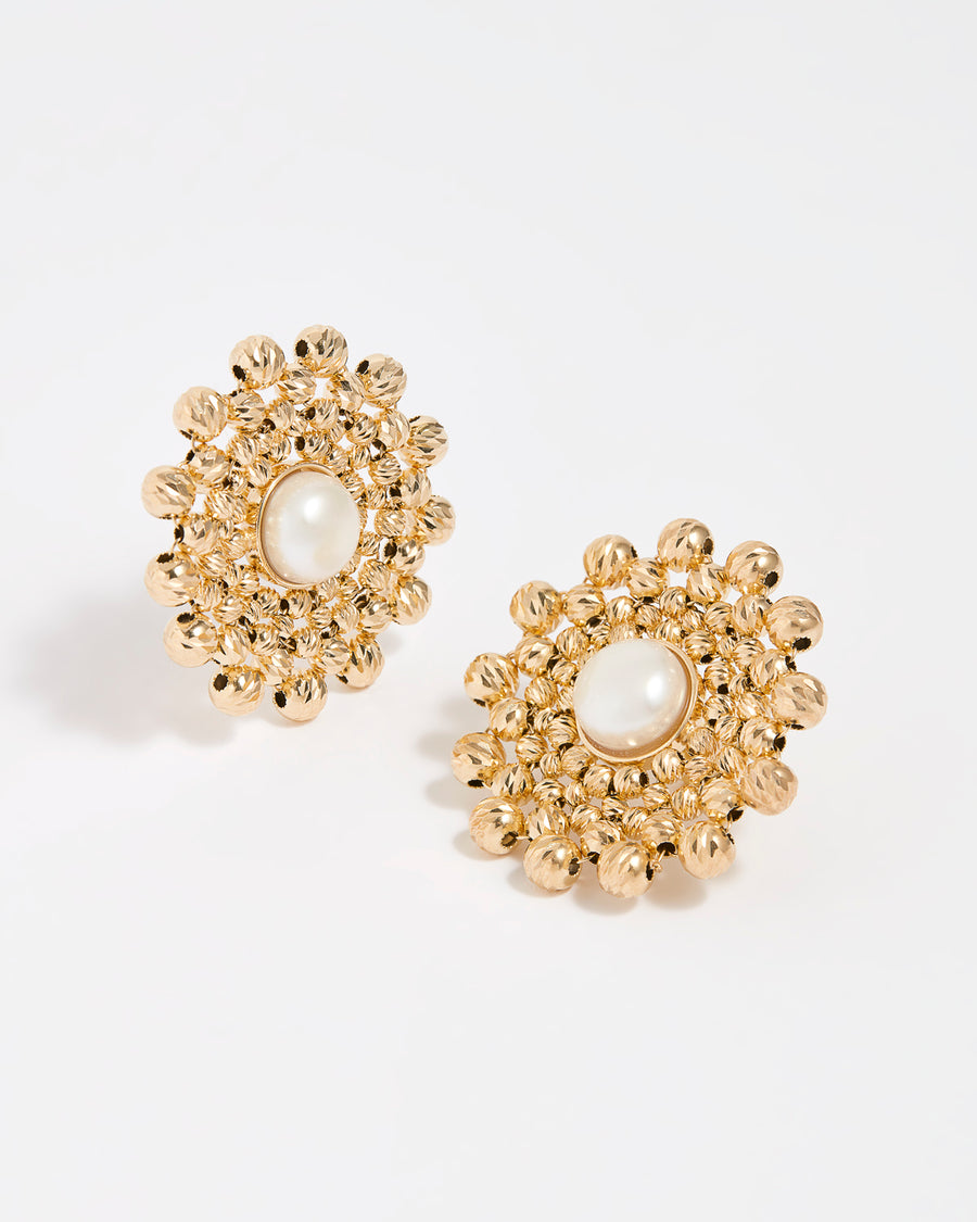 Close up product shot of gold flower shaped beaded earrings featuring a centre pearl gemstone on a white background