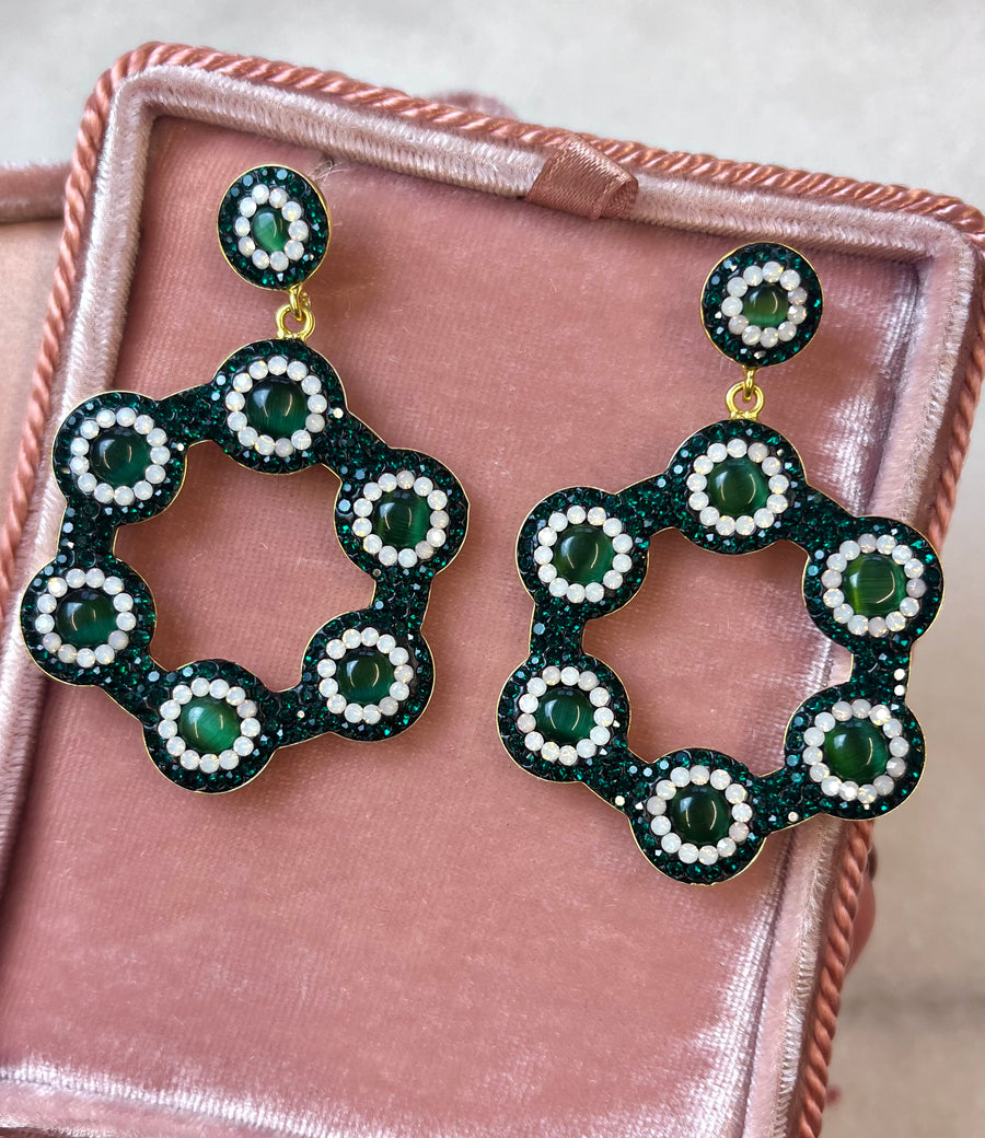 Emerald green hoop earrings with vibrant green cat’s eye gemstones, surrounded by sparkling emerald crystals and white accents, set in 18k gold-plated silver, displayed in a pink velvet box.