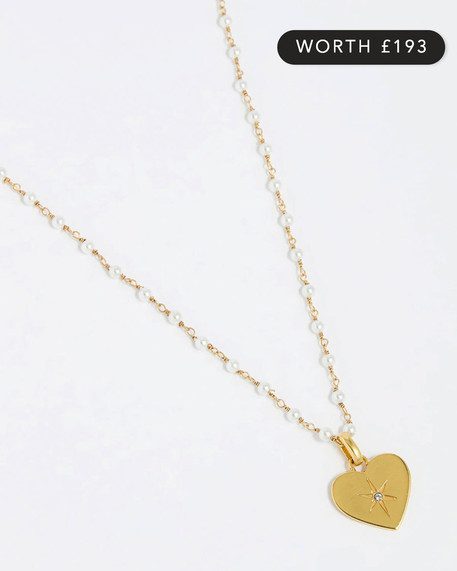 Image of pearl charm neckace, the charm features a clear crystal surrounded by a star etching set in a shiny gold heart.