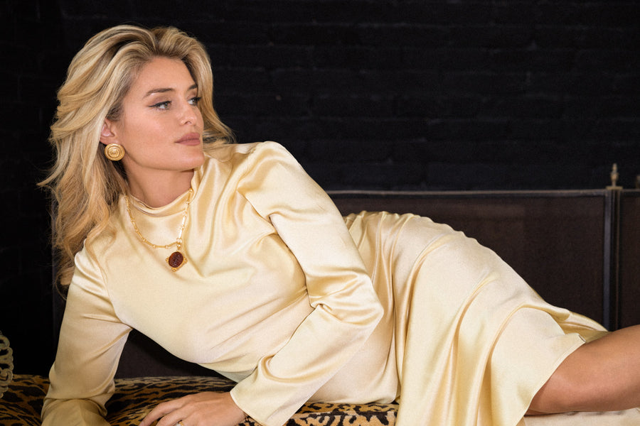 daphne oz laying down in front of the fire wearing a satin dress and gold jewellery from her collaboration with soru 
