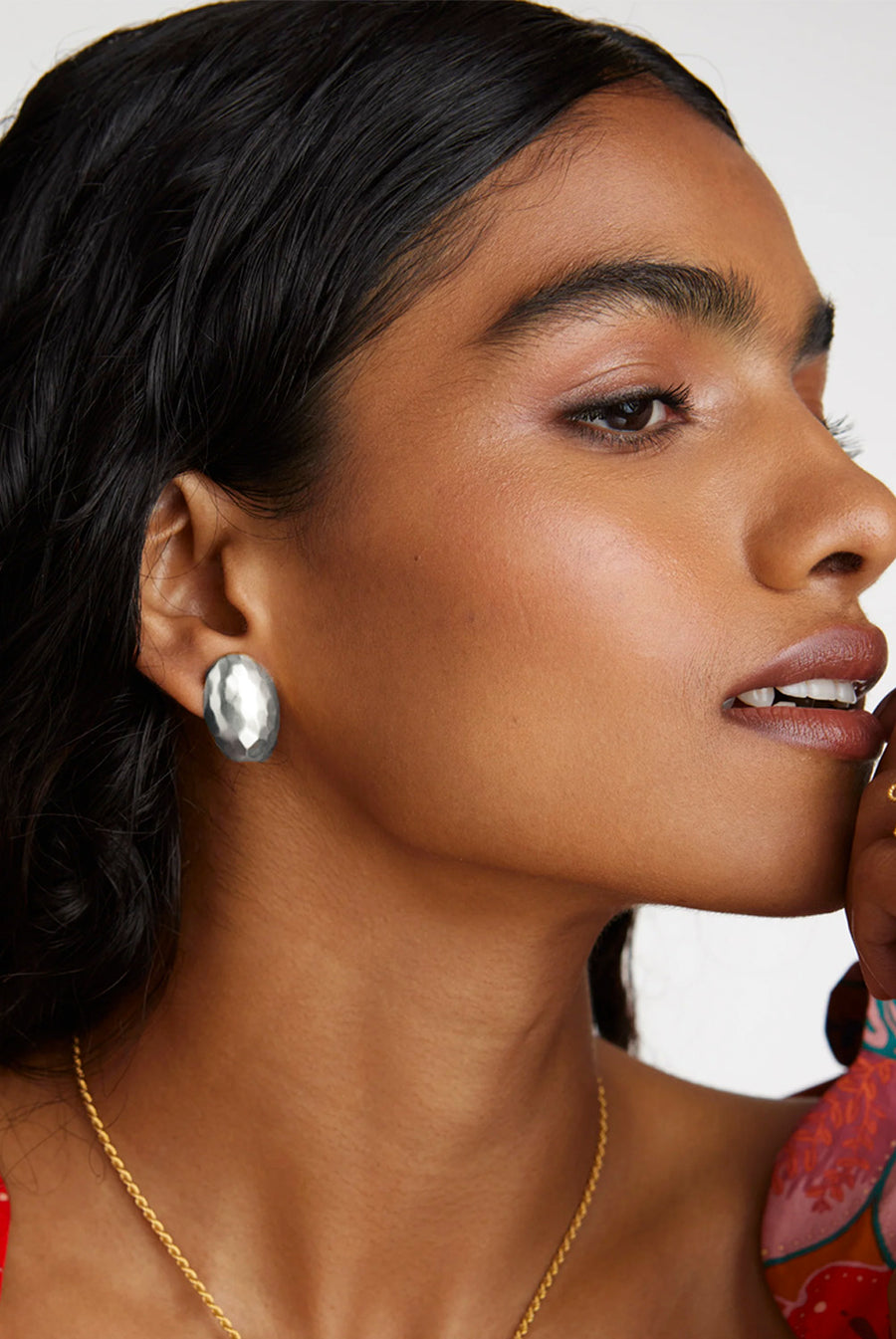 A model shot of a lady wearing modern silver stud earrings, featuring a delicate hammered effect to the surface