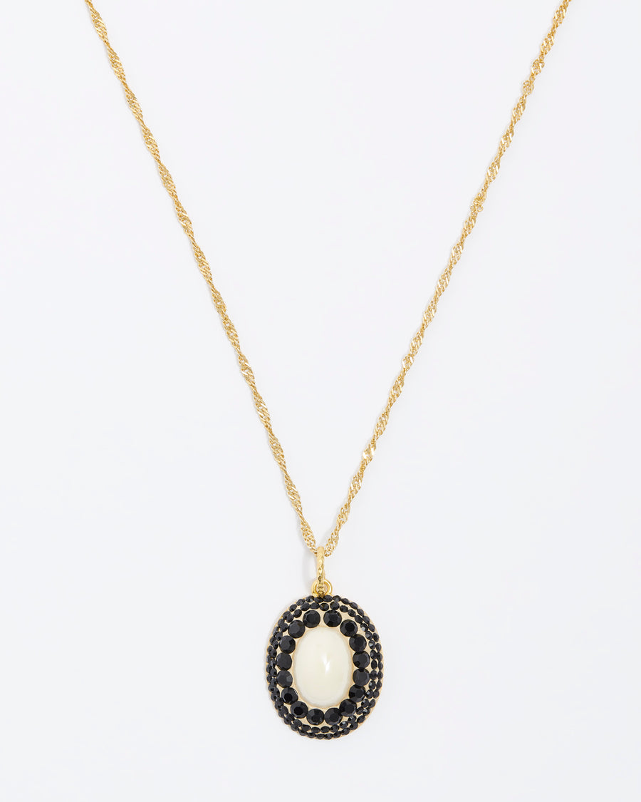 close up front facing shot on white background of the majorca pearl and black crystal pendant on gold chain 