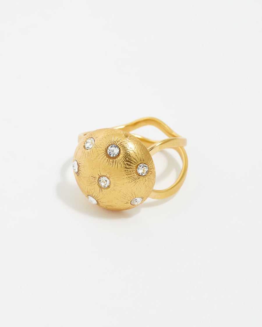 close up image shot of round gold star etched ring with clear crystal embellishment on a white back ground