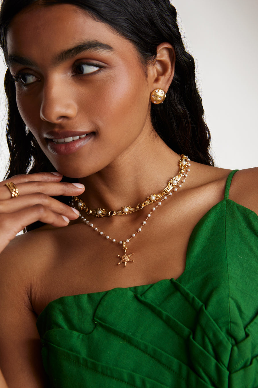 Model shot wearing link necklace with pearl detail layered with pearl detail charm necklace and a nautical charm.  Worn with gold stud earrings and a gold ring