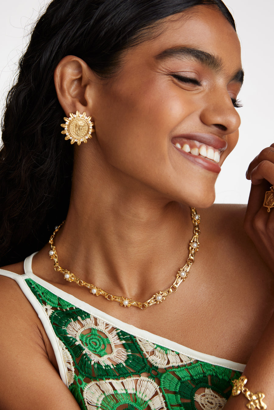 model shot wearing the soru jewellery gold link necklace with pearl detail, gold coin earrings and a chunky gold bracelet while smiling