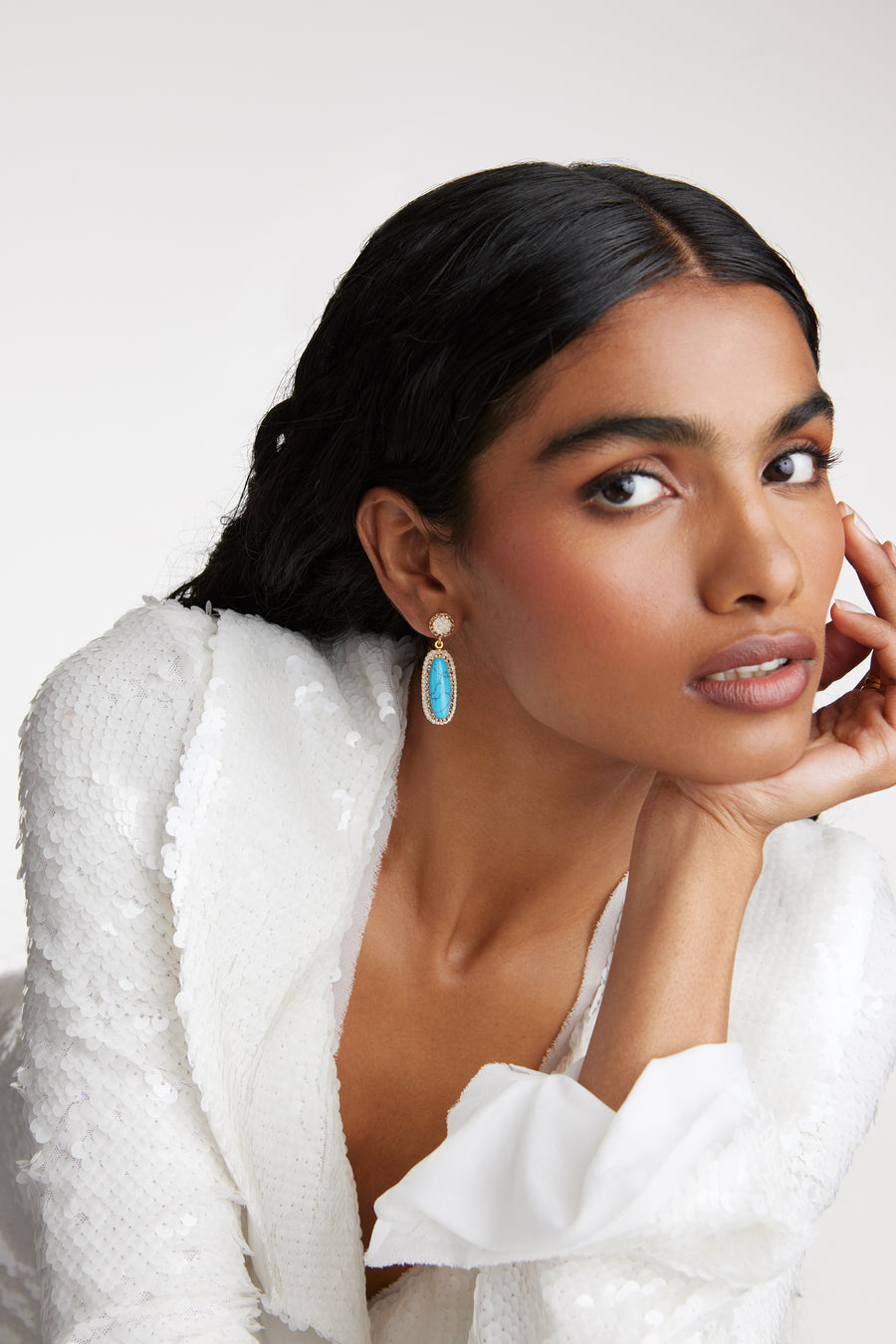 Model shot wearing the Soru Jewellery turquoise gemstone long oval earrings surrounded by white crystals