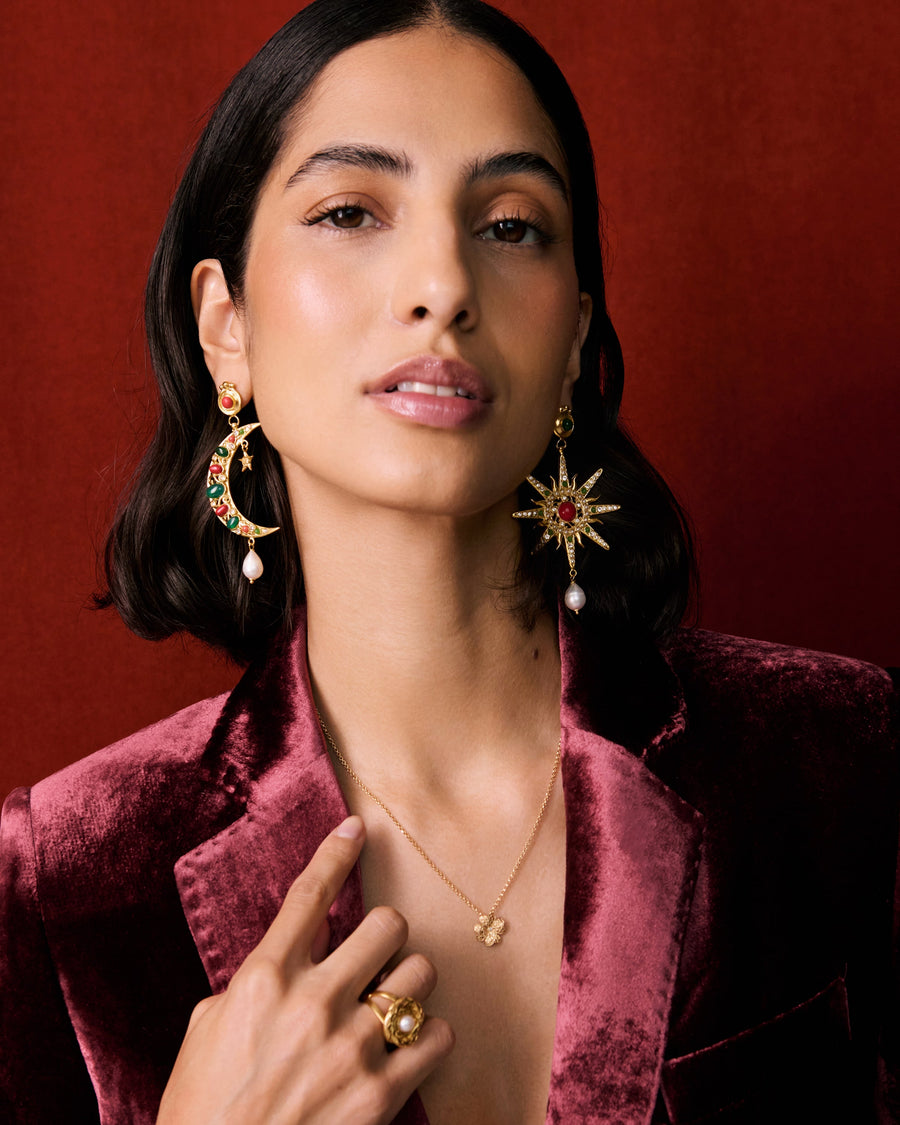 model wearing moon and star earrings and the clover necklace with a red velvet blazer and red backdrop