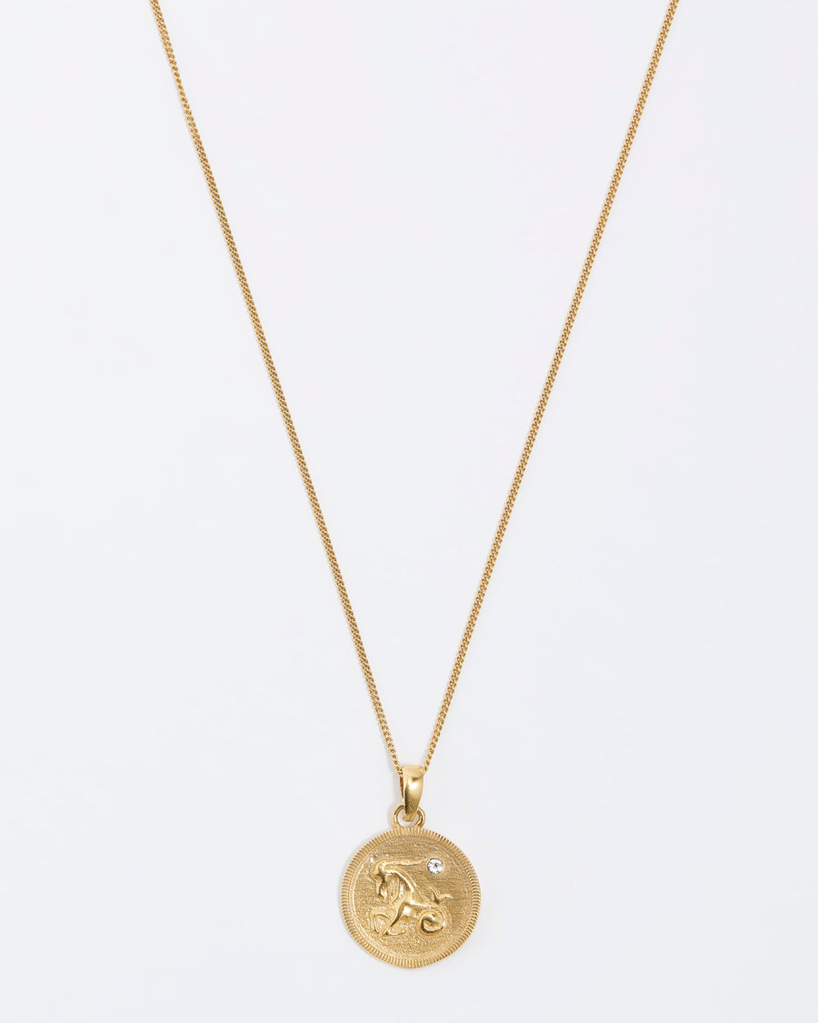 Capricorn Zodiac circular gold pendant on a fine gold chain necklace.