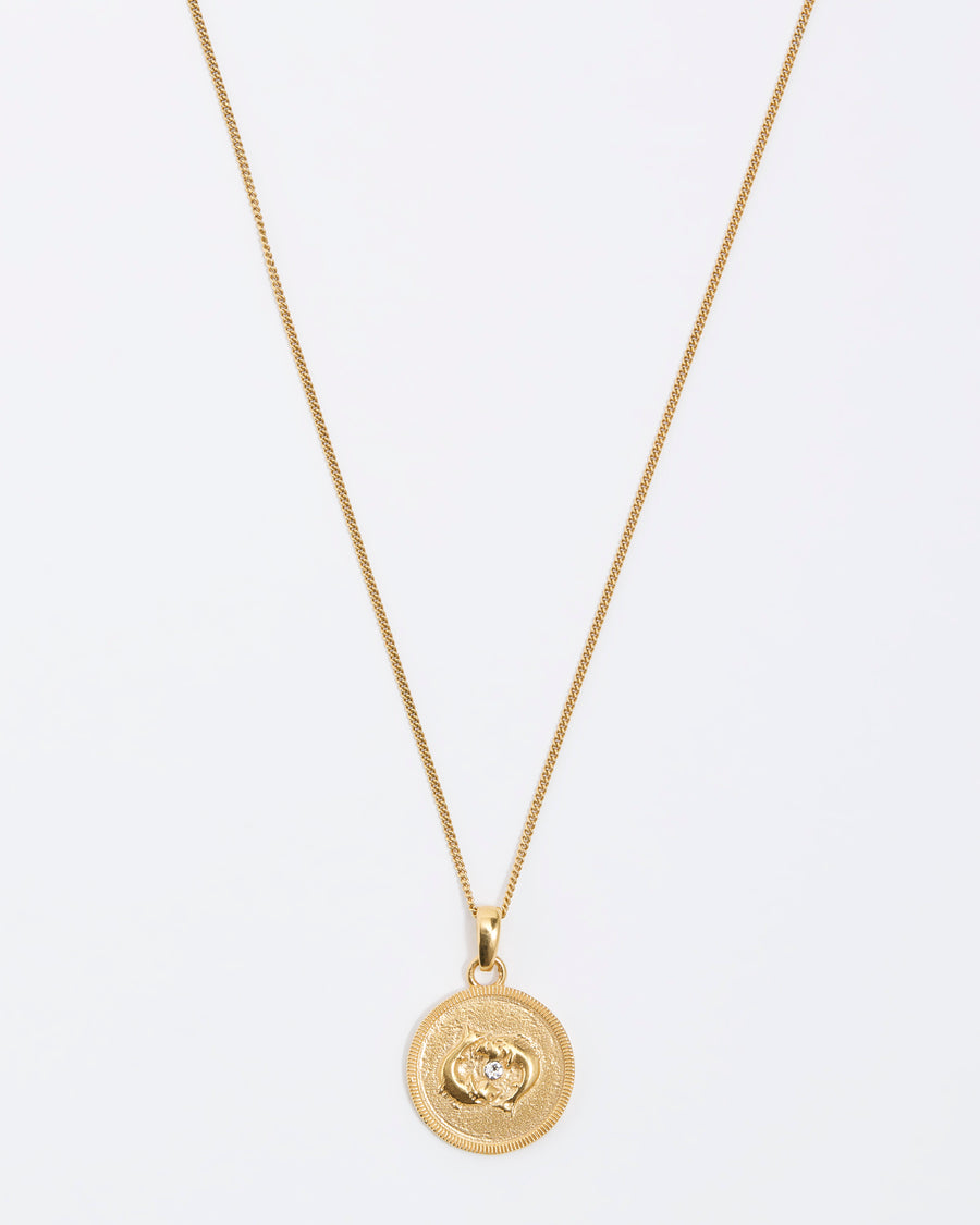 Pisces Zodiac circular gold pendant on a fine gold chain necklace.