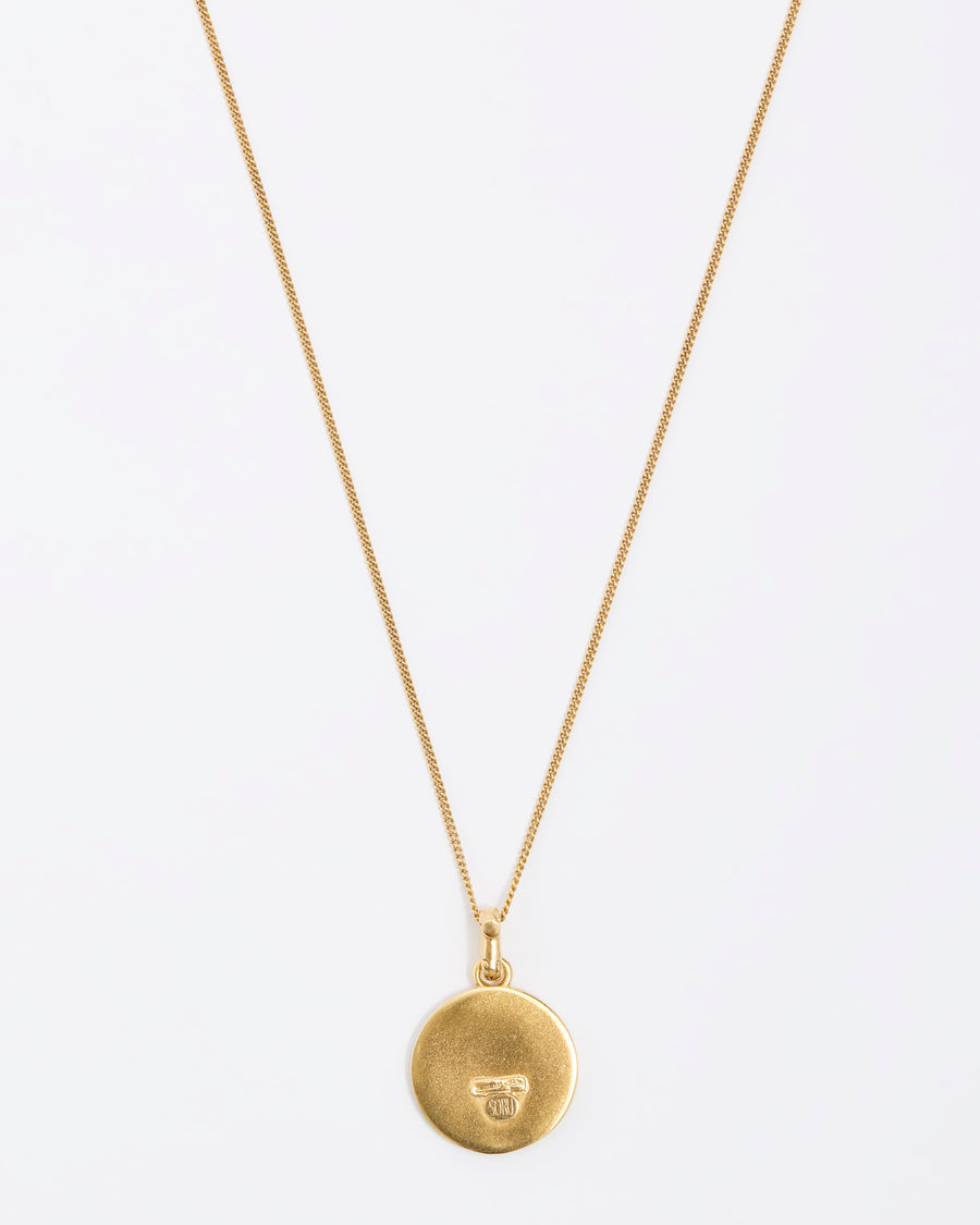 Back of zodiac circular gold pendant on a fine gold chain necklace.